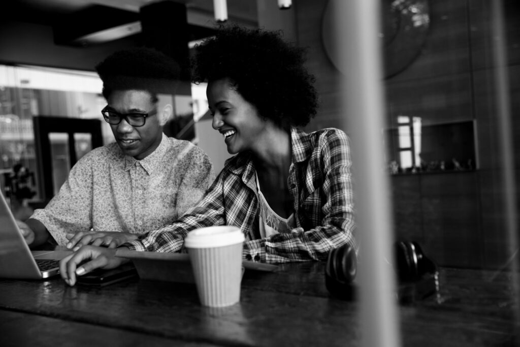 Two Young Businesspeople Working On Laptop In Coffee Shop