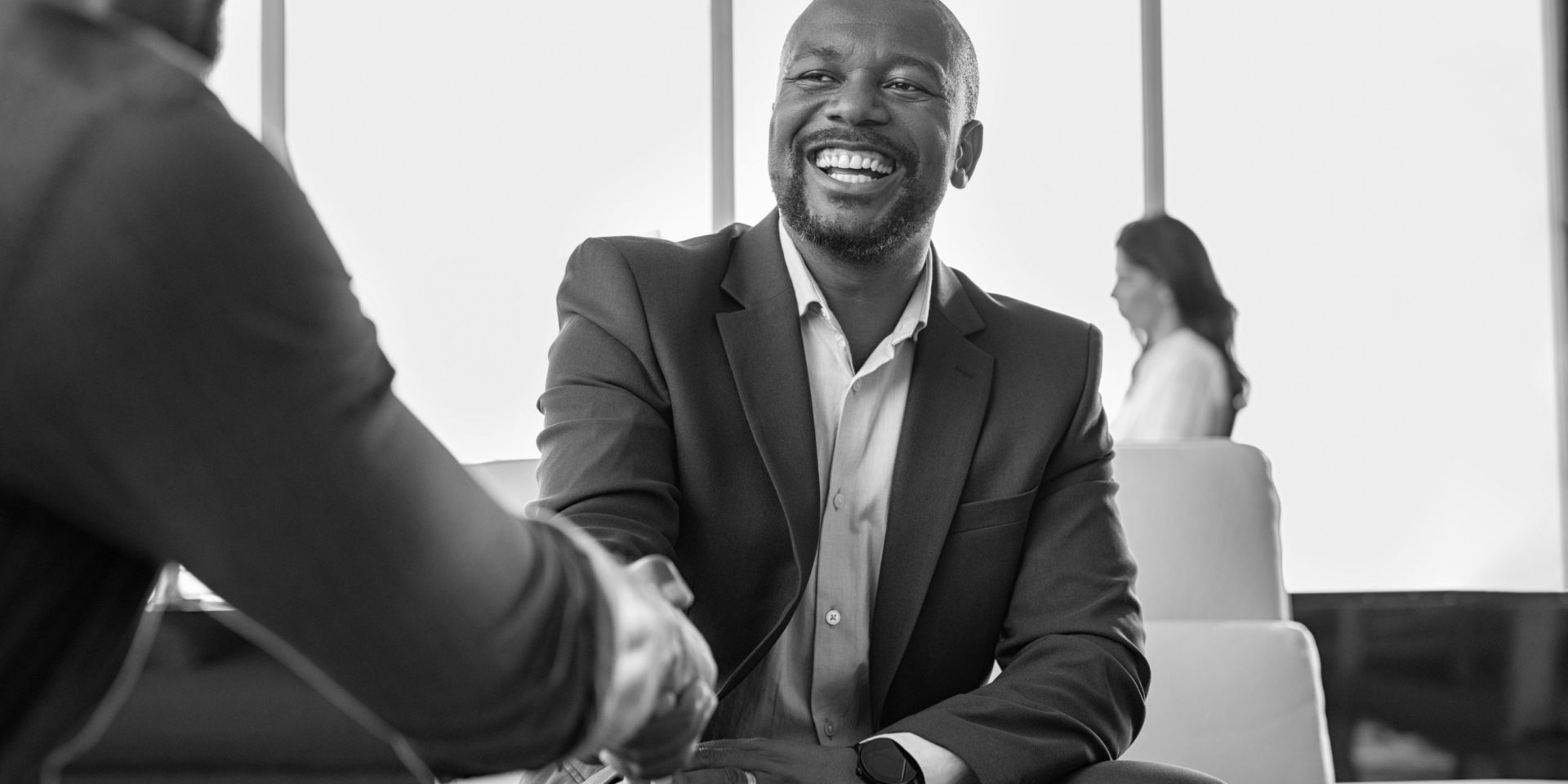 Two happy mature business men shaking hands in office. Successful african american businessman in formal clothing closing deal with handshake. Multiethnic businessmen shaking hands during a meeting.