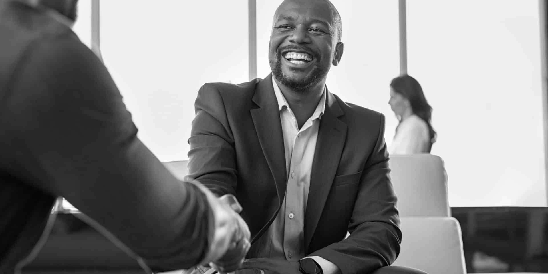 Two happy mature business men shaking hands in office. Successful african american businessman in formal clothing closing deal with handshake. Multiethnic businessmen shaking hands during a meeting.